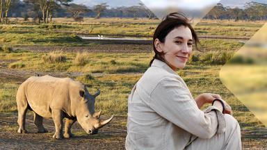 Sibel Kekilli sitzt in Savanne vor Nashorn