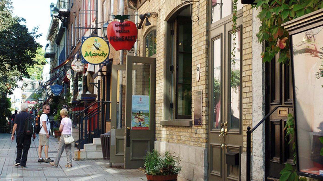 Häuserzeile, vor der Menschen bummeln. 