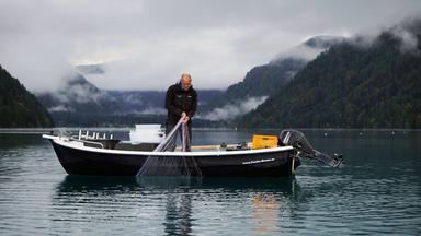 Ein Mann mit Netz auf einem Fischerboot.