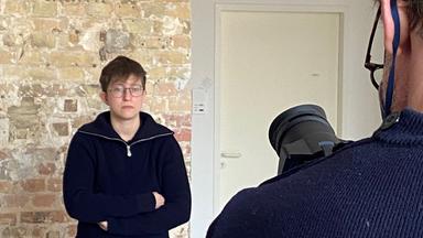 Mann vor Backsteinwand wird gefilmt