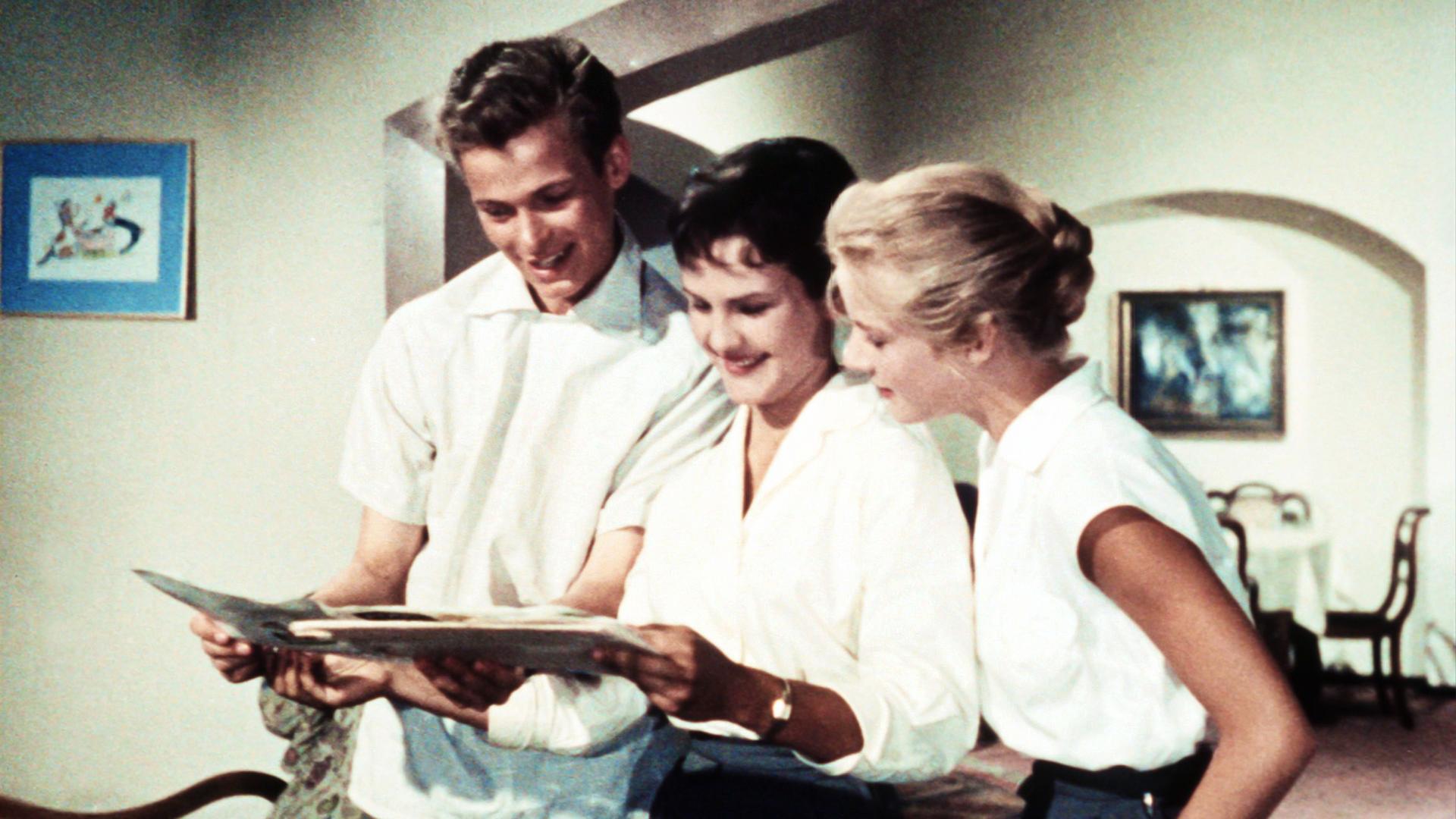 Ein Mann und zwei Frauen betrachten ein Magazin.