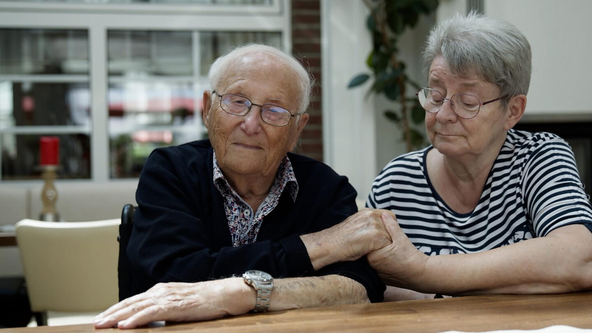 Ein älterer Mann und ein ältere Frau halten einander die Hand.