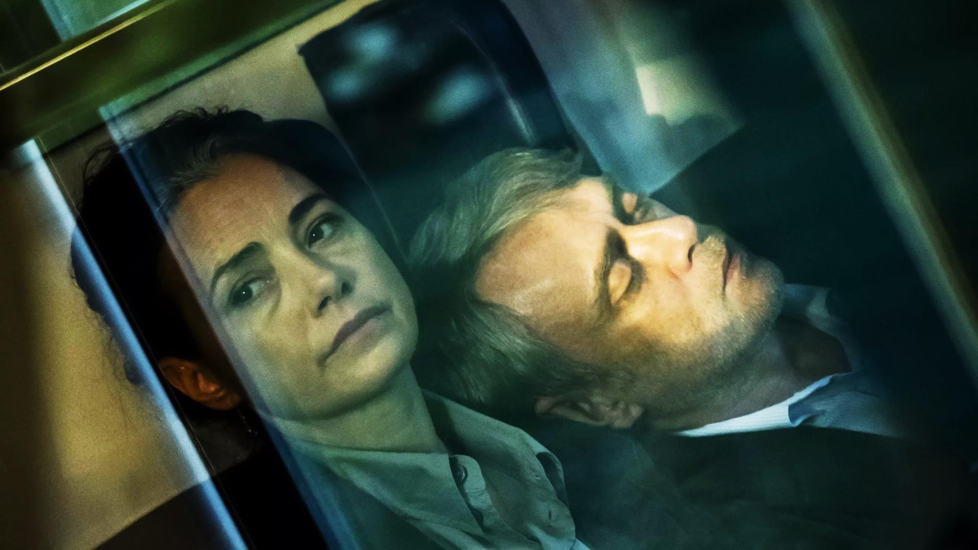 Ein Frau schaut aus einem Zugabteil nach draußen, an ihrer Schulter lehnt ein schlafender Mann.