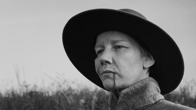 Auf einer Schwarz-Weiß-Fotografie sieht man eine Frau mit einem großen Hut.