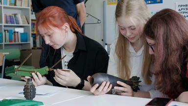Mädchen sitzen an einem Tisch und halten Sprengsätze in den Händen.