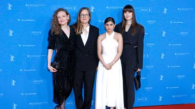 Vier Frauen stehen vor dem blauen Hintergrund der Berlinale-Pressekonferenz auf einem roten Teppich. Drei Frauen mittleren Alters tragen dunkle Anzüge und Kleider, eine jüngere Frau trägt ein schulterfreies weißes Kleid.