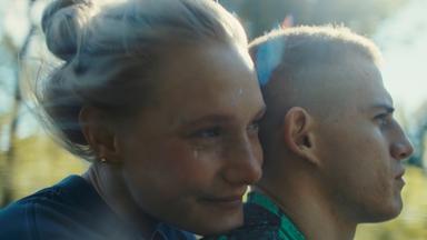 Eine junge Frau sitzt hinter einem jungen Mann auf einem Motorrad.