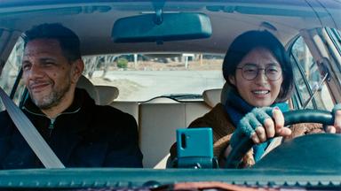 Eine Frau und ein Mann sitzen in einem fahrenden Auto.