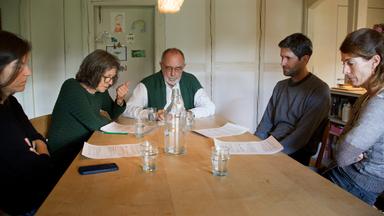 Eine Familie sitzt an einem Tisch.