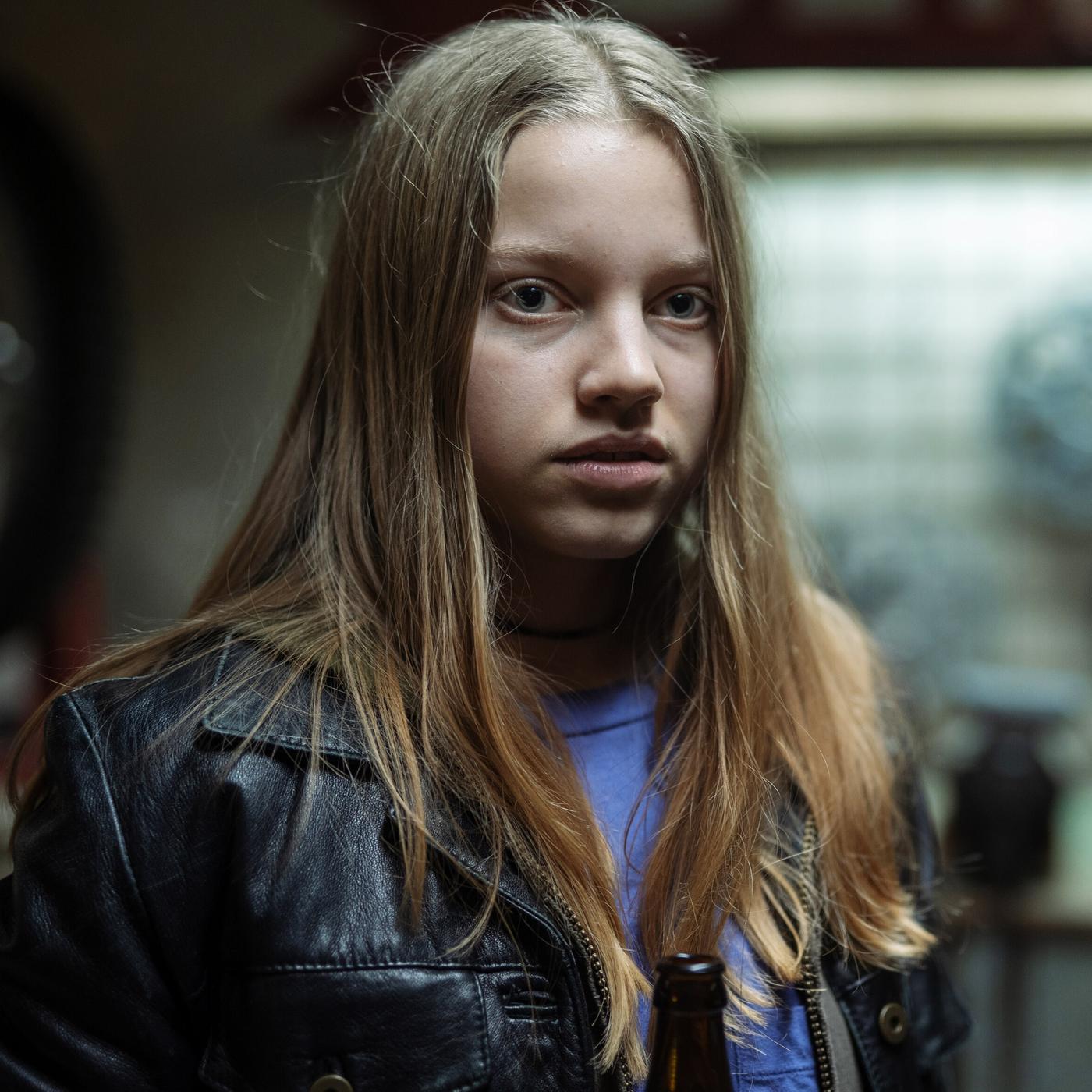 Ein junges Mädchen mit blauem Shirt und einer schwarzen Lederjacke