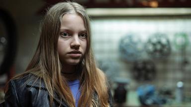 Ein junges Mädchen mit blauem Shirt und einer schwarzen Lederjacke