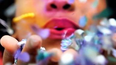 Ein rot bemalter Mund bläst in Blütenblätter