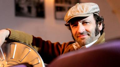 Mann mit Schieberkappe sitzend mit einer Kinorolle