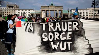 Jugendliche halten vor dem Brandenburger Tor ein Banner hoch. 