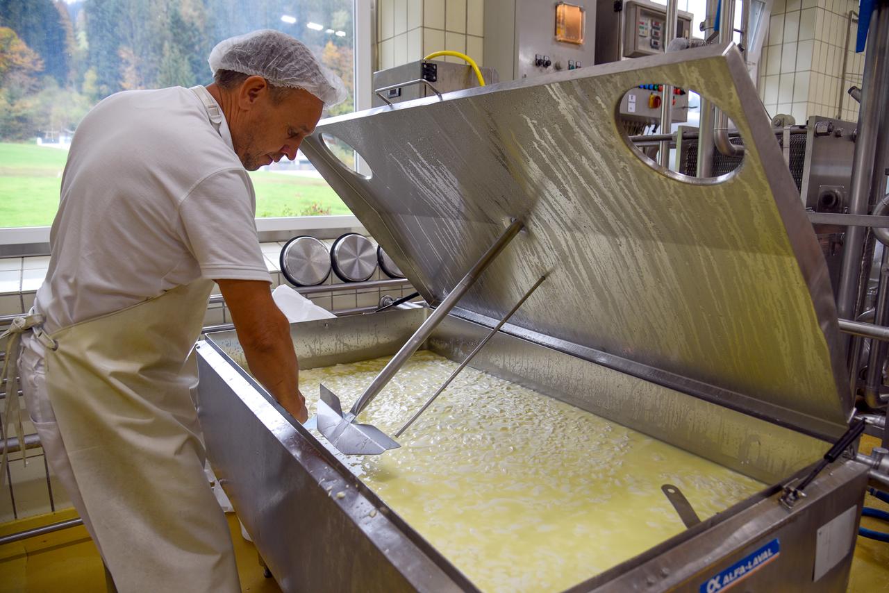 Mann rührt geronnene Milch in großer Wanne