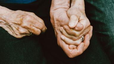 Ein älteres Paar hält sich an den Händen.