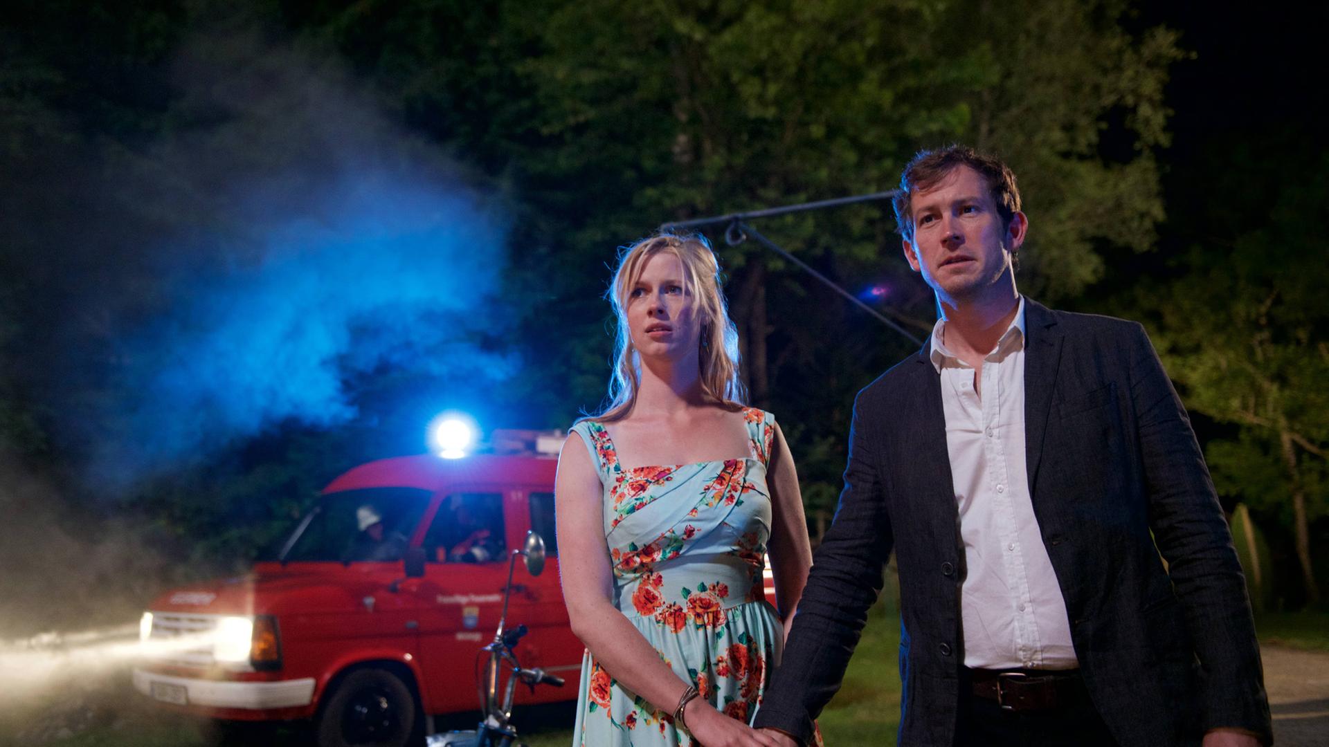 "Marie fängt Feuer": Marie (Christine Eixenberger) und Stefan (Stefan Murr) stehen im Dunkel auf einer Wiese und schauen auf die brennende Hütte.