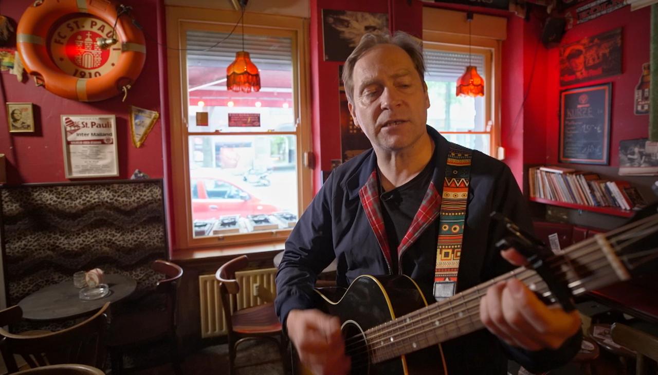 Mann mit Gitarre in Fußballkneipe