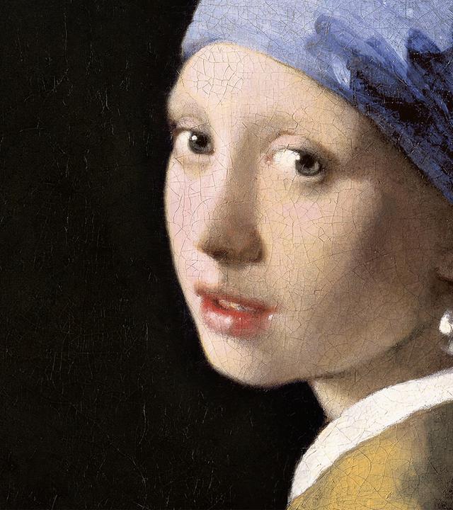 Porträt einer jungen Frau mit blauem und gelbem Kopftuch, gelber Kleidung und einem großen Perlenohrring vor dunklem Hintergrund.