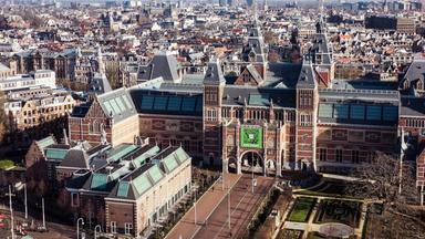 Luftaufnahme eines großen Gebäudes mit mehreren Türmen aus rotem Backstein in einer Großstadt (Amsterdam)