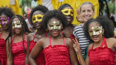 Gruppenfoto: Frau mit jungen kostümierten Kolumbianerinnen mit Augenmasken.