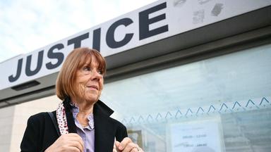 Eine ältere Frau mit kinnlangen glatten Haaren steht vor einem Gebäude mit der Aufschrift Justice.