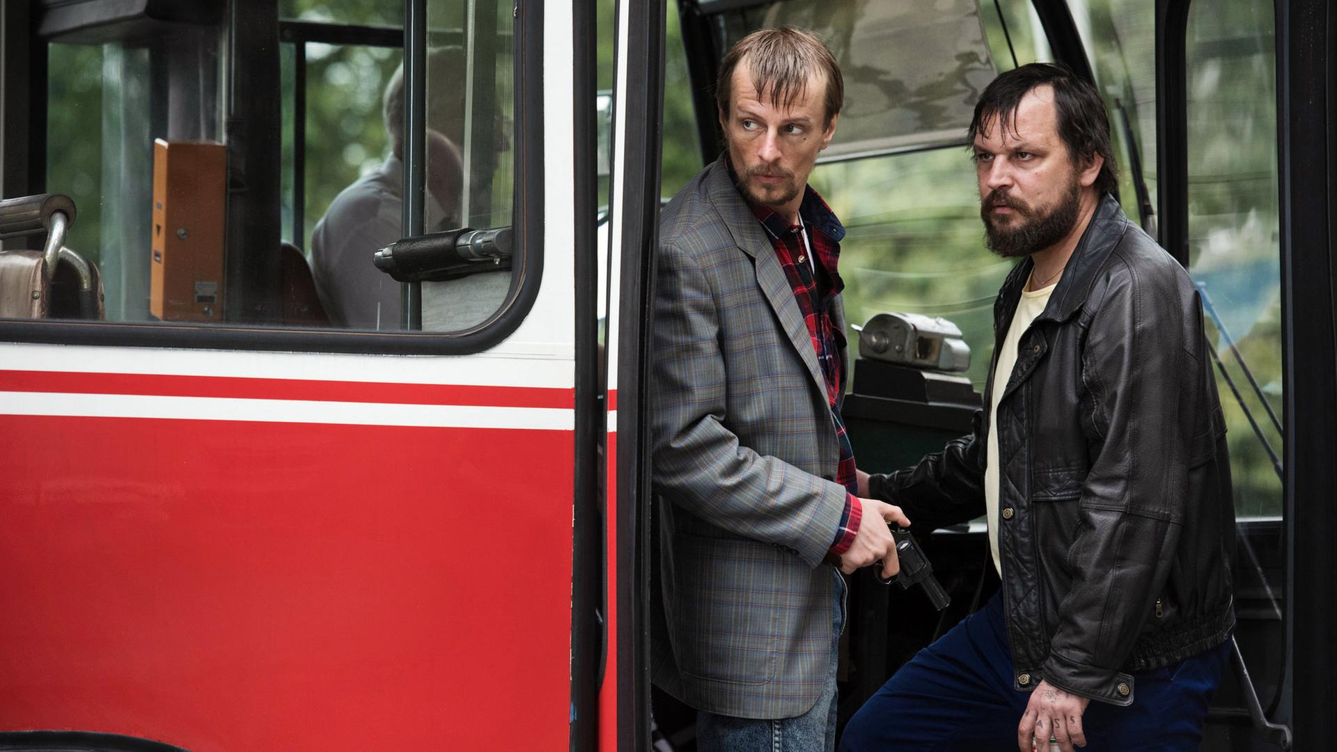 Zwei Männer schauen grimmig aus einem Buss 