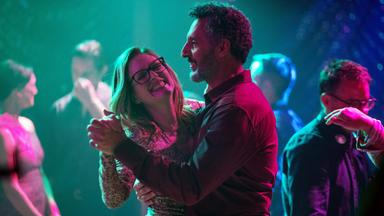 Ein Mann und eine Frau tanzen miteinander, sie lacht ausgelassen.  