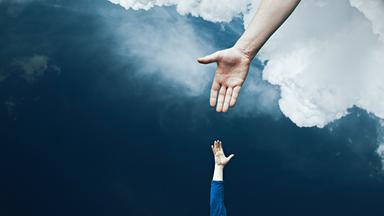 Aus Wolken reicht ein großer Arm einem nach oben ausgestreckten Arm die Hand