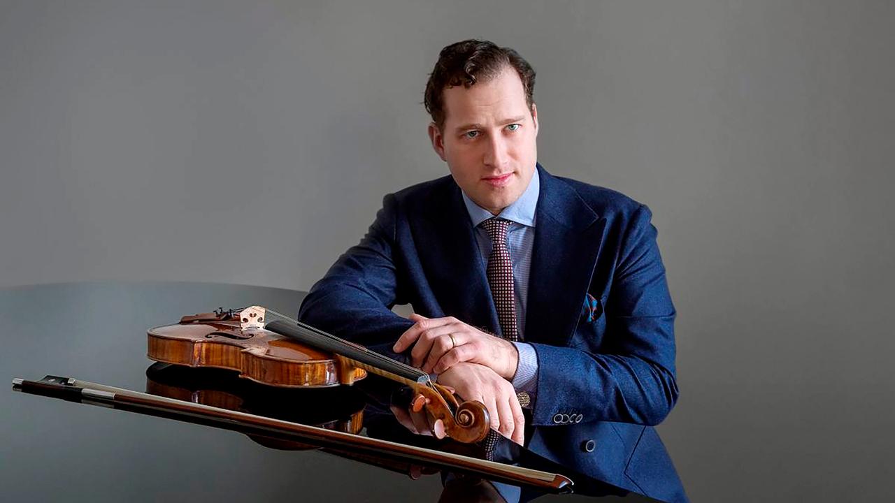 Ein Mann lehnt an einem Flügel, auf dem eine Geige liegt.