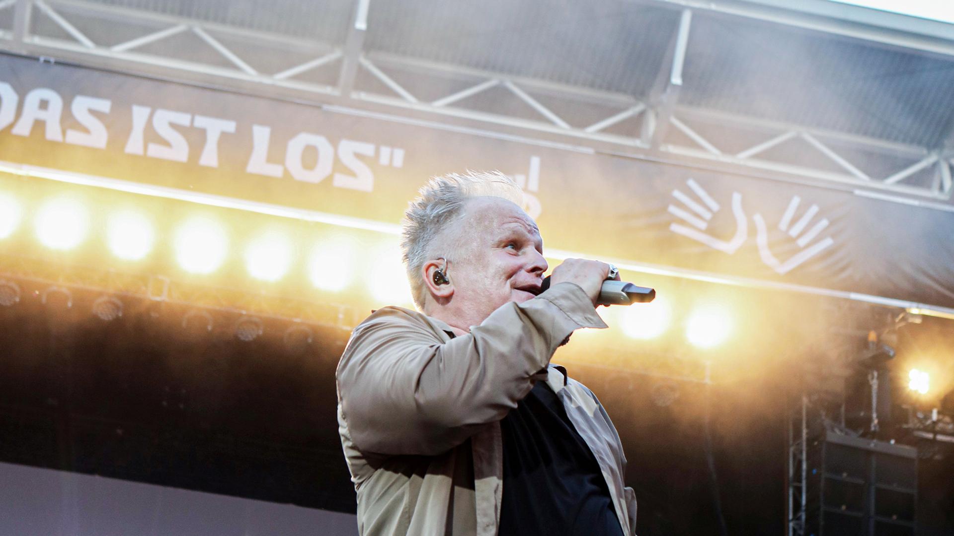 Herbert Grönemeyer steht singend auf der Bühne. Im Hintergrund sieht man den Schriftzug: Das ist los.