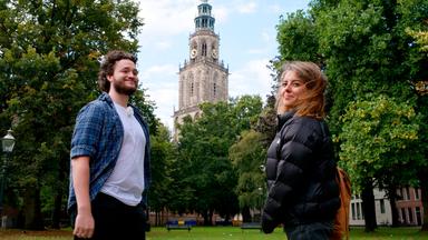 Ein Mann und eine Frau in einem kleinen Park. Im Hintergrund ein alter Kirchturm.