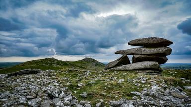 Faszinierender Blick auf die ikonischen Felsformationen von Dartmoor vor einem dramatischen, bewölkten Himmel.