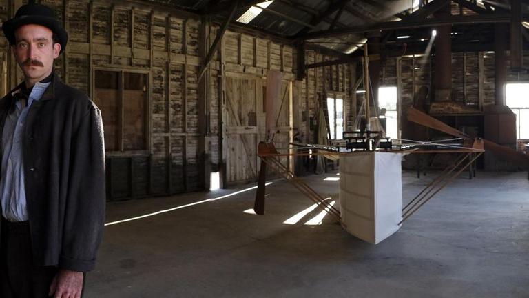 Spielszene: Gustav Weißkopf vor seiner Flugmaschine Nr. 21.