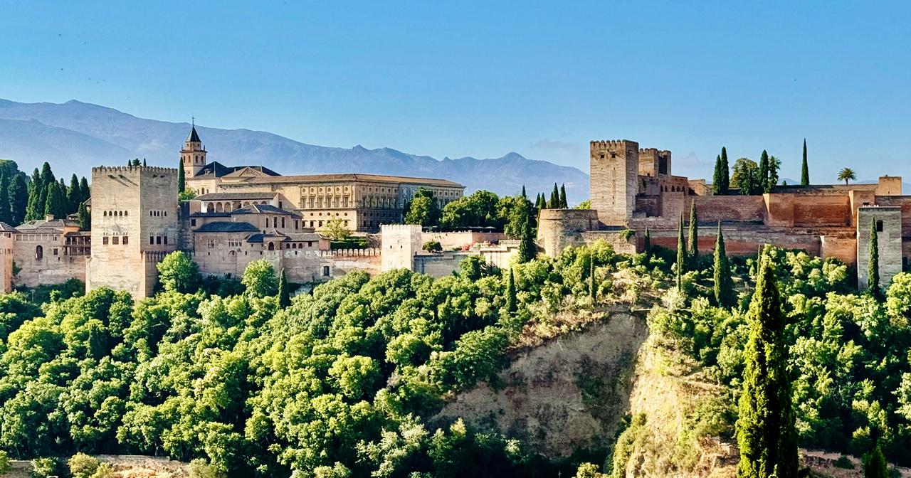 Eine große Burganlage auf einem Berg vor blauem Himmel
