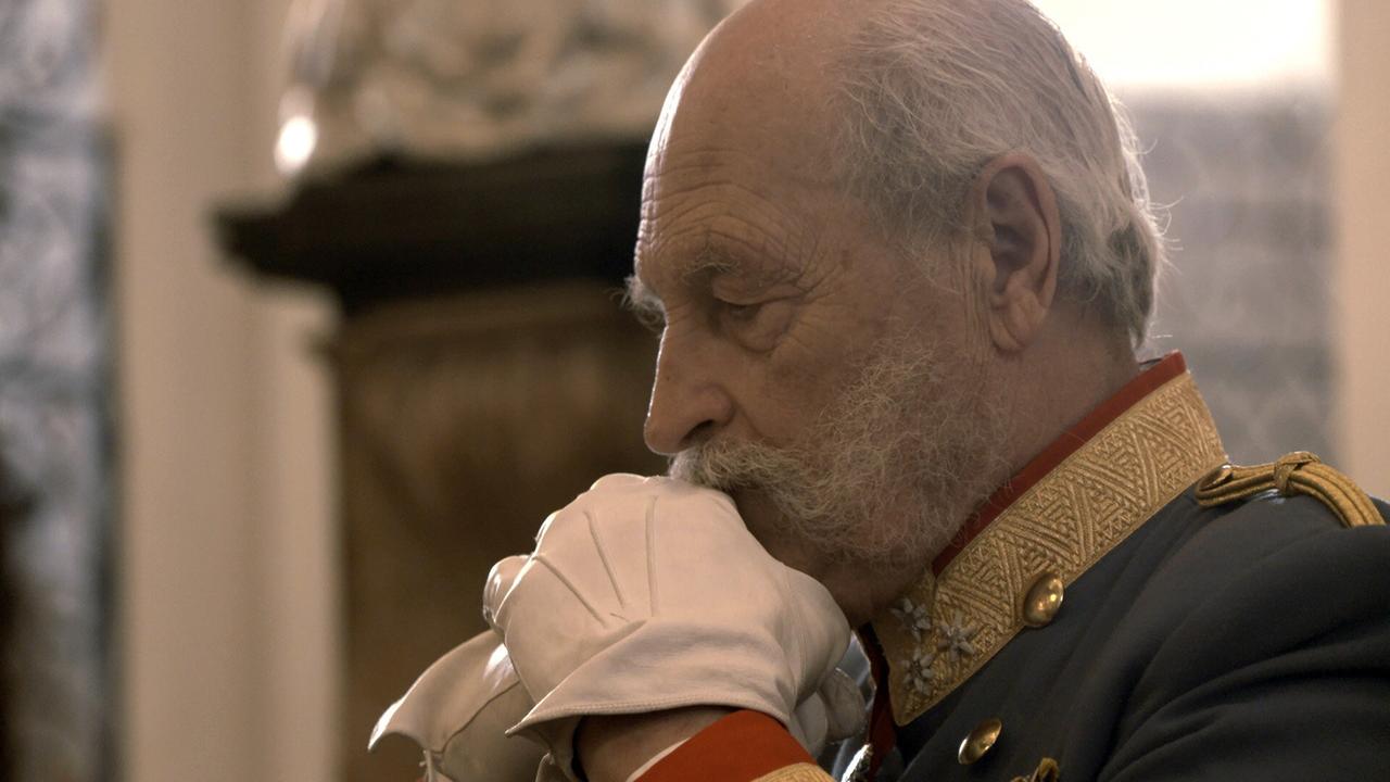 Ein älterer Mann in historischer Uniform, der Kaiser Franz Joseph darstellt, hält seine behandschuhten Hände zum Gebet gefaltet.