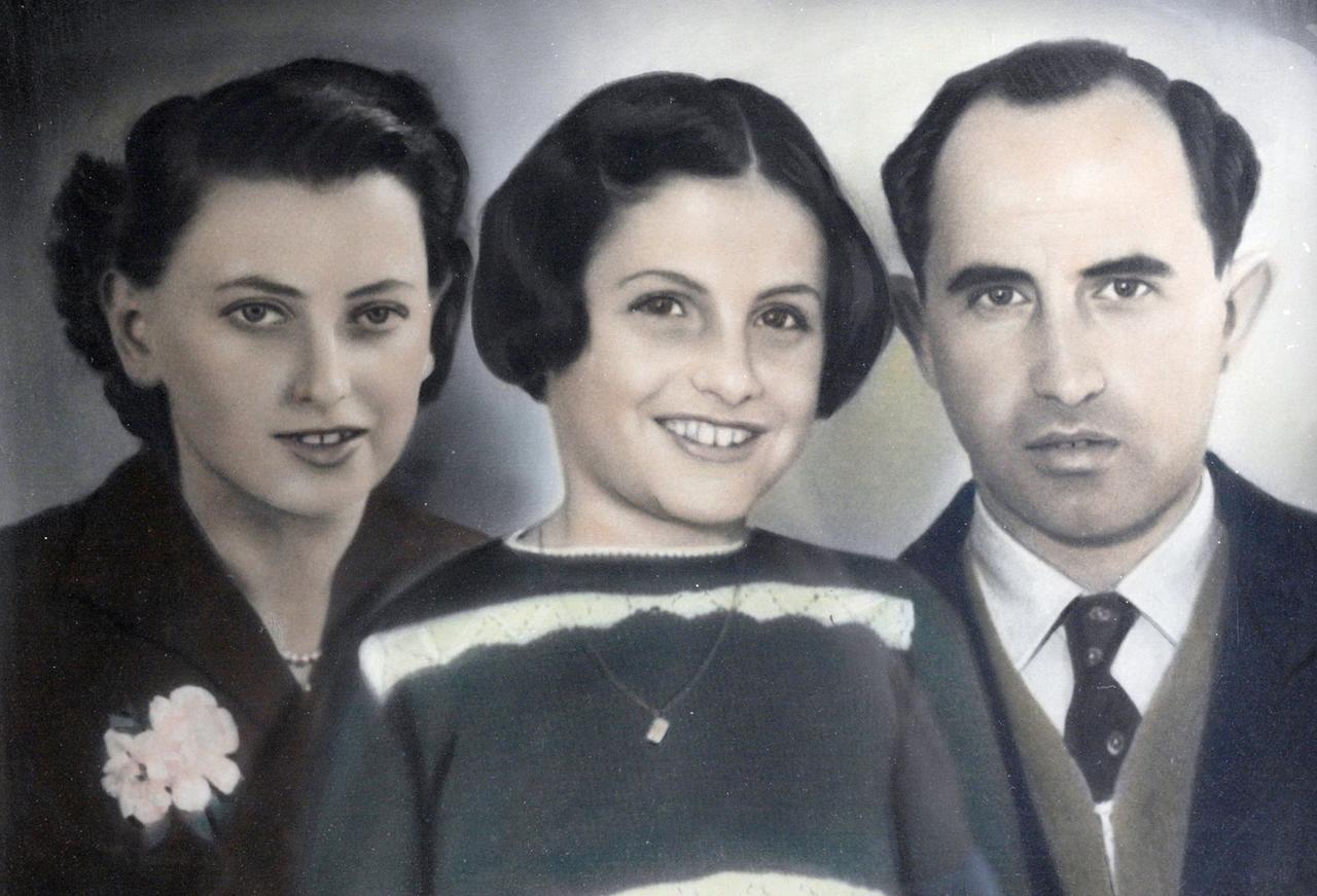 Das Bild zeigt eine farbige Porträtillustration von drei Personen, die eng miteinander verbunden sind. In der Mitte steht ein Mädchen mit kurzen, lockigen Haaren, das ein breites Lächeln trägt und einen Pullover mit einem auffälligen, geometrischen Muster anhat. Auf ihrer linken Seite steht eine Frau mit schulterlangen, gewellten Haaren, die ein dunkles Oberteil mit einer Blumenbrosche trägt. Sie hat einen sanften, aber selbstbewussten Gesichtsausdruck. Auf der rechten Seite steht ein Mann mit kurz geschnittenem Haar und einem ernsthaften Gesichtsausdruck, der einen Anzug mit einem Kragenhemd trägt. Der Hintergrund des Bildes ist sanft und neutral, sodass die Figuren im Vordergrund stark betont werden.