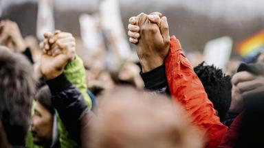 Nahaufnahme von einer Menschenmenge, mit hochgereckten Händen, die sich halten