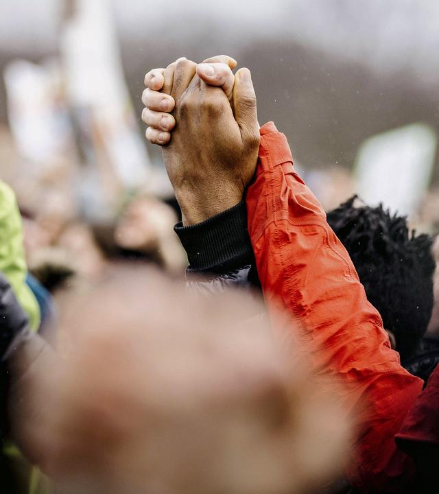 Nahaufnahme von einer Menschenmenge, mit hochgereckten Händen, die sich halten