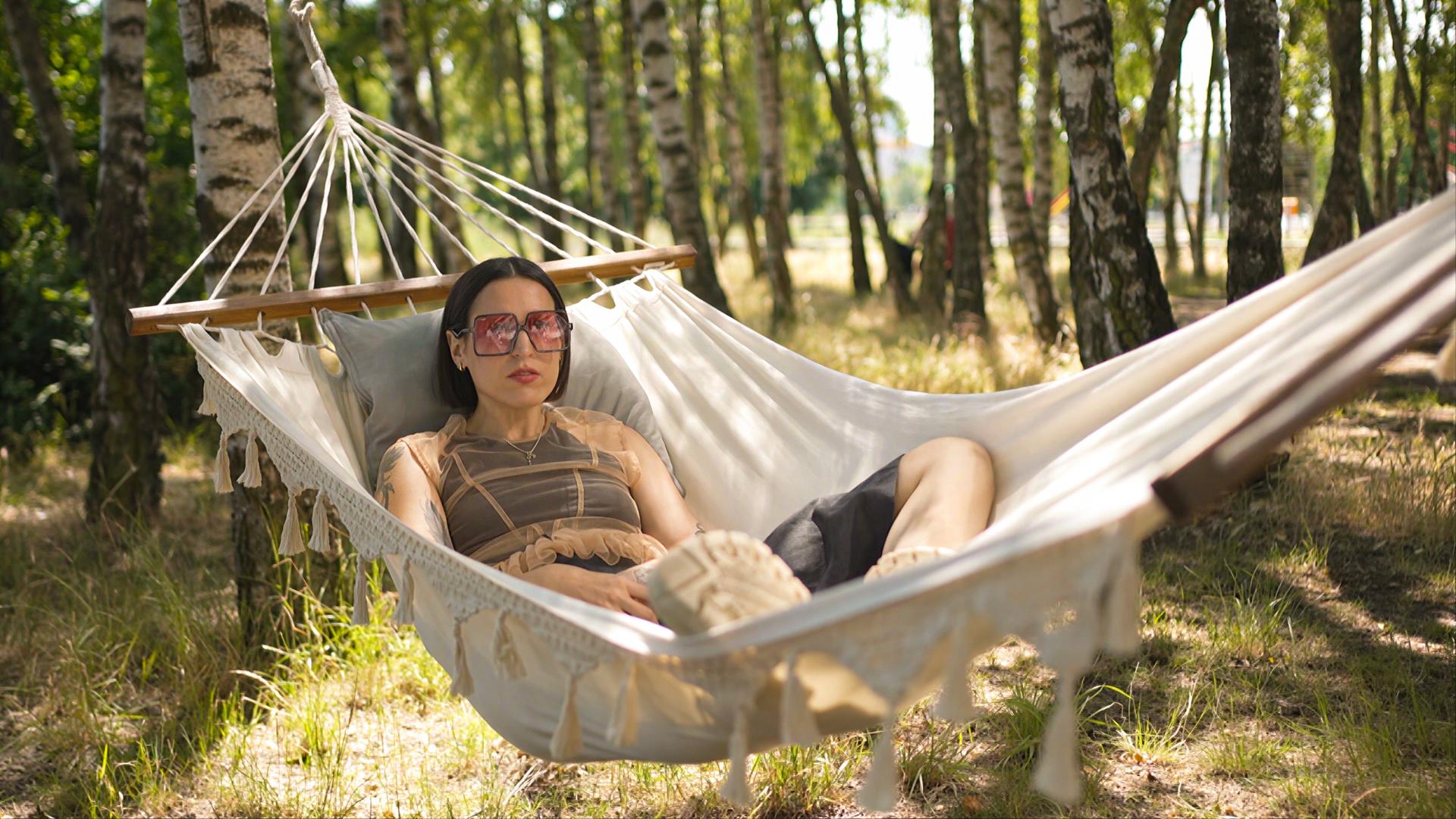 Frau mit Sonnenbrille liegt im Wald in einer Hängematte
