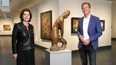 Eine Frau und ein Mann stehen im Museum rechts und links einer Frauenstatue.