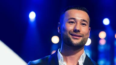 Porträtfoto des Ex-Boxers Hamid Rahimi im Anzug auf einer beleuchteten Bühne.