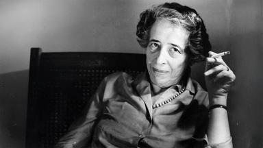 Altes Schwarz-Weiß-bild von einer Frau mittleren Alters, die sich in einem Stuhl zurücklehnt und eine rauchende Zigarette zwischen zwei Fingern hält.