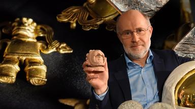 Harald Lesch steht mit einer kleinen Steinkugel in der Hand inmitten von Requisiten.