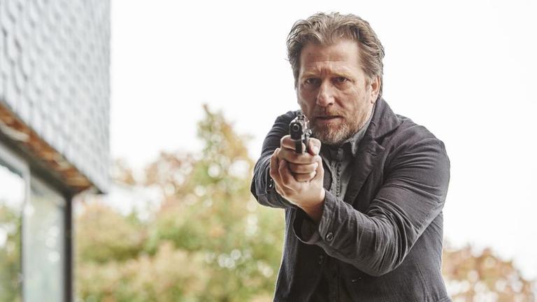 "Hattinger und der Nebel": Alfons Hattinger (Michael Fitz) in Großaufnahme mit gezogener Waffe.