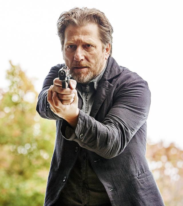 Hattinger und der Nebel": Alfons Hattinger (Michael Fitz) in Großaufnahme mit gezogener Waffe.