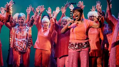 Bunt gekleidete singende alte Menschen.