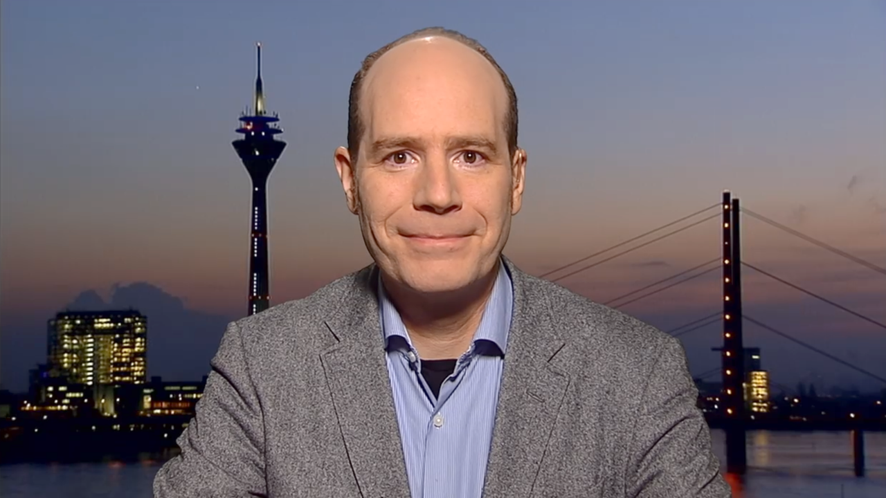 Ein Mann mit Anzug lächelt.