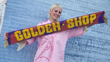 Helene Bukowski, Autorin des Buchs "Wer möchte nicht im Leben bleiben", hält einen Schal mit der Aufschrift "Golden Shop" in den Händen