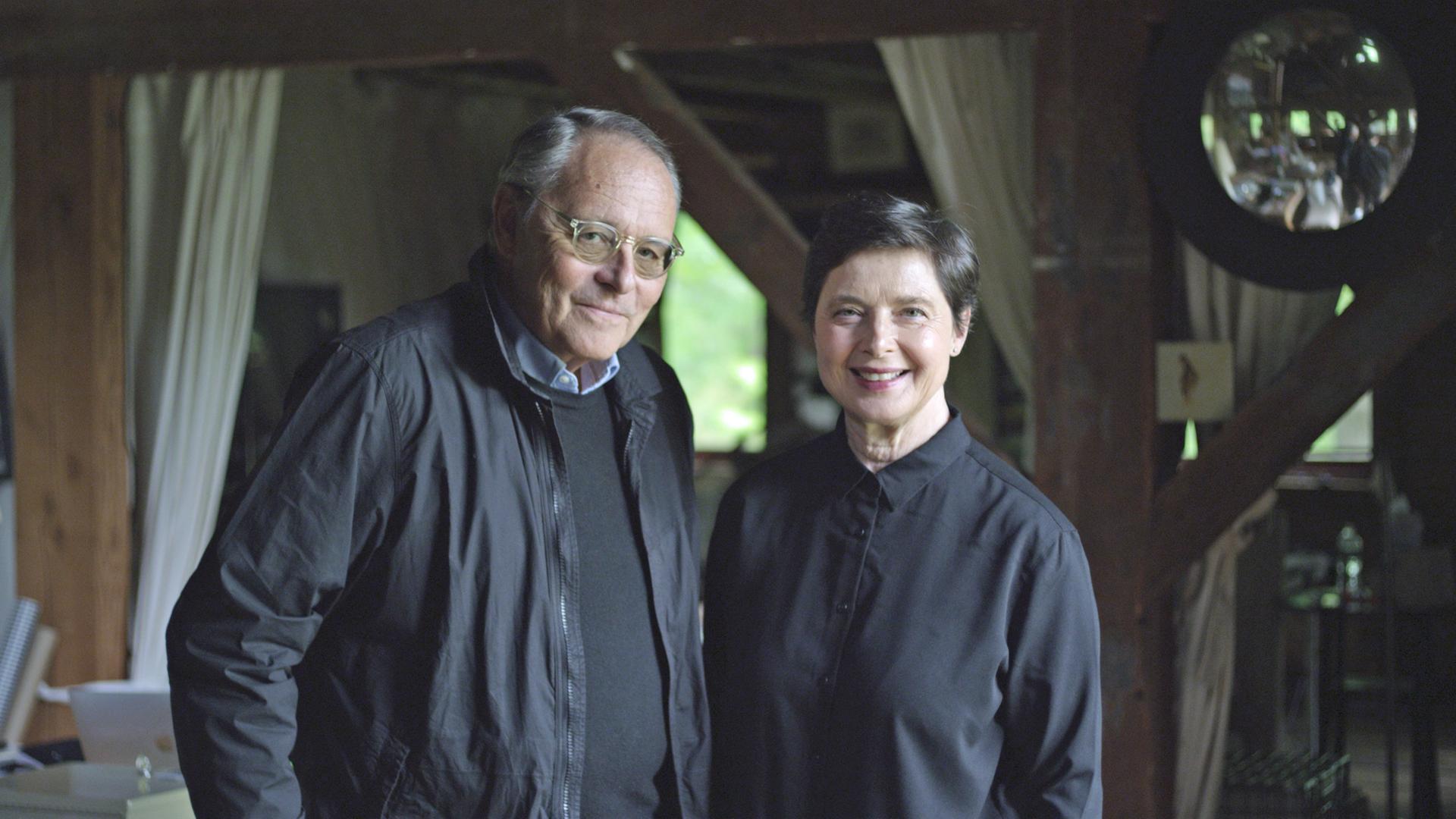 Auf dem Foto sieht man die Schauspielerin Isabella Rossellini und den Filmemacher Gero von Boehm. Die beiden stehen nebeneinander und lächeln. Sie tragen beide schwarze Kleidung. 
